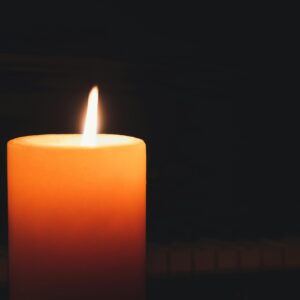Close-up of a glowing candle in the dark, highlighting warmth and serenity.