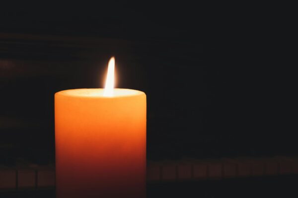 Close-up of a glowing candle in the dark, highlighting warmth and serenity.