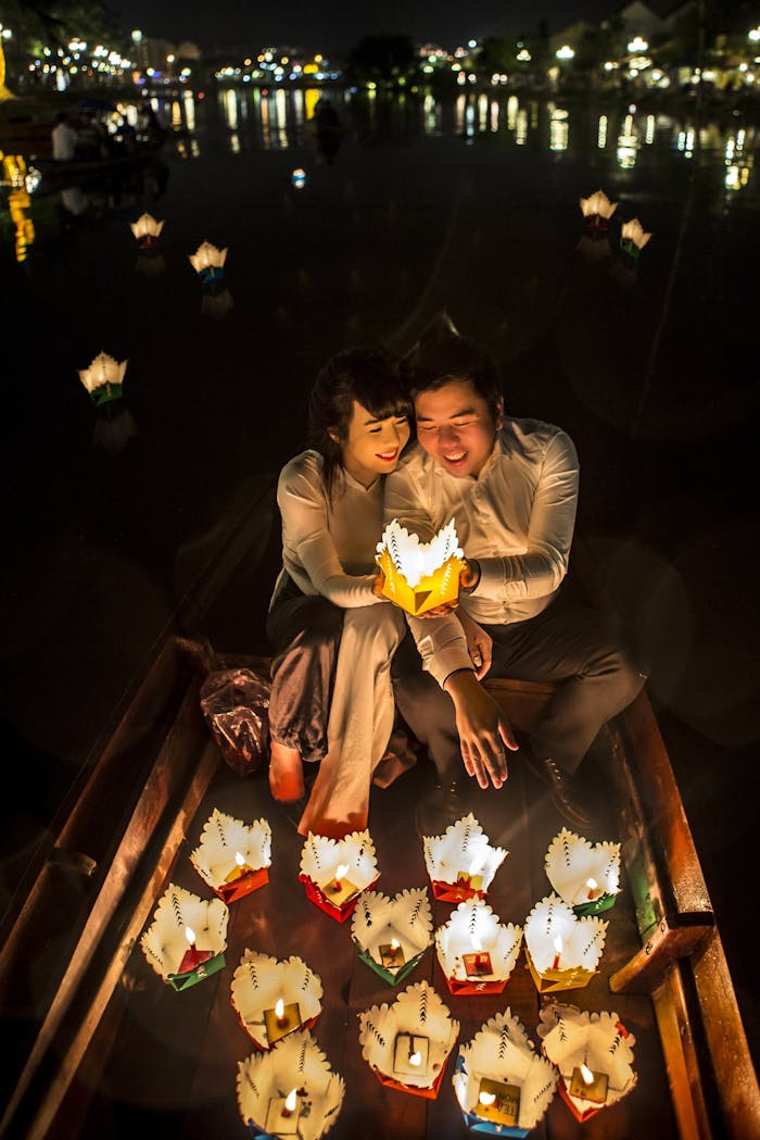 services-03 Couple releasing glowing paper lanterns during a night ceremony on a boat, symbolizing love and togetherness.
