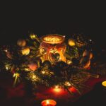 Warm and festive candle arrangement with pine branches and ornaments, perfect for holiday decor.