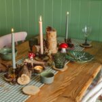 Charming nature-inspired table setting with candles, wood elements, and autumn decor, perfect for cozy gatherings.