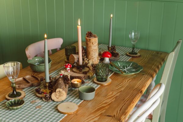 Charming nature-inspired table setting with candles, wood elements, and autumn decor, perfect for cozy gatherings.