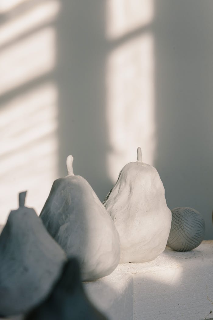 gallery-6 Handcrafted pear-shaped candles in soft light casting artistic shadows.