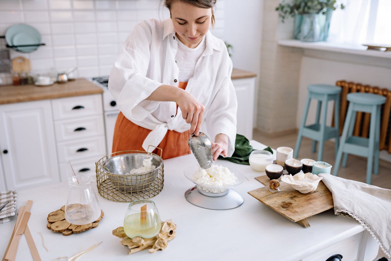 our-experience Woman crafting candles at home with natural wax in a bright kitchen setting.