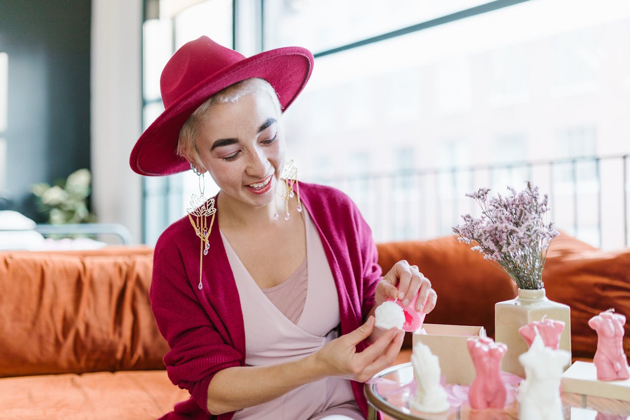 why-choose-us Stylish woman in red hat joyfully unboxing handcrafted candles in cozy living room.