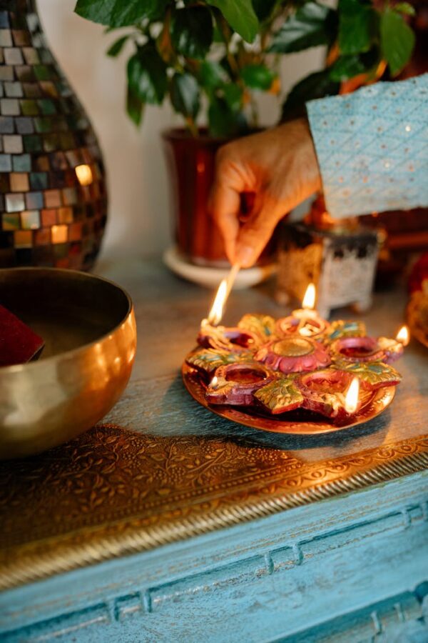 A hand lighting an oil lamp for Diwali celebration indoors with decorative elements.